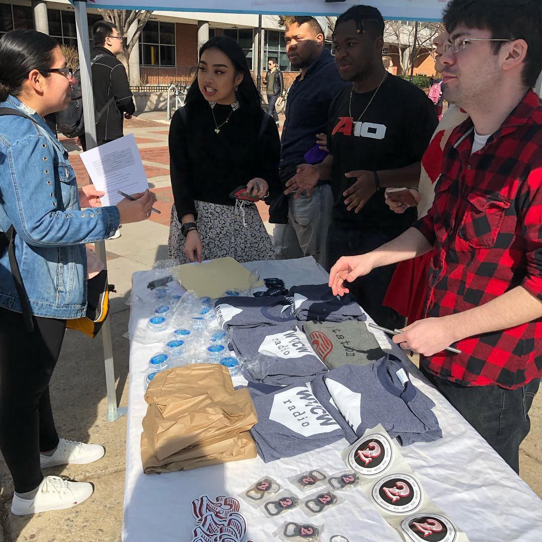 WVCW Radio staff members hand out swag and talk with students during a recruitment event st The Compass.